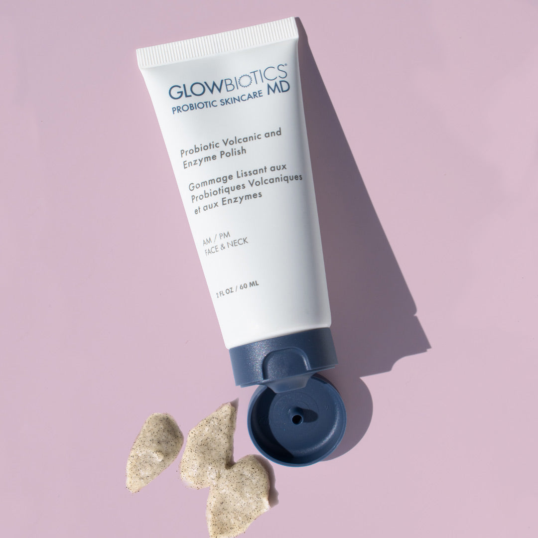 Glowbiotics Probiotic Volcanic and Enzyme Polish tube lying on a pale pink background with the cap open and product squeezed out next to it