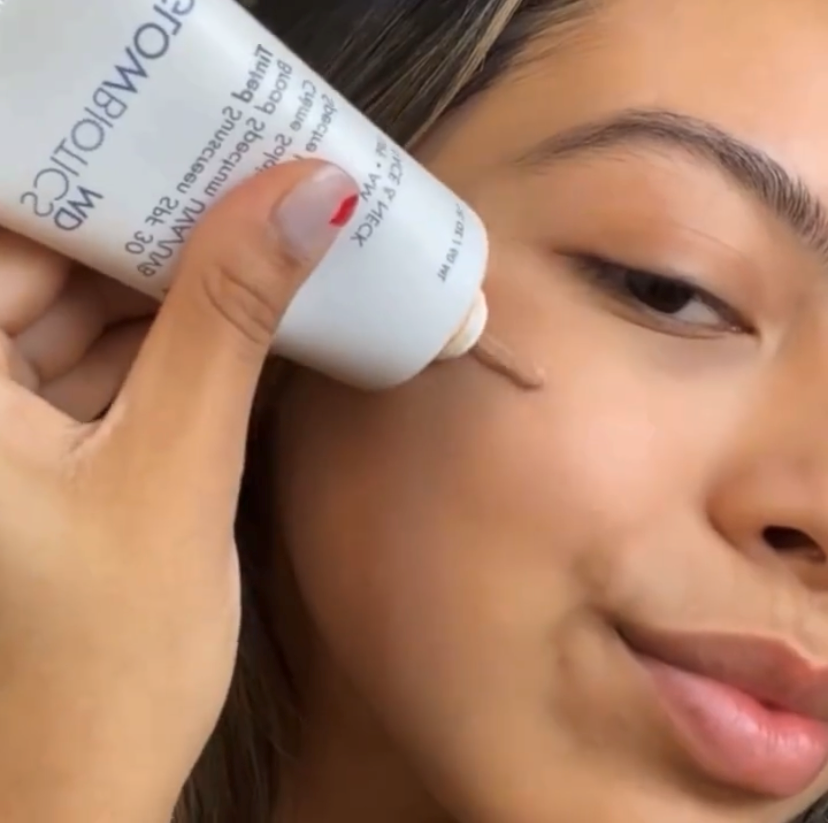Close-up of a person applying Glowbiotics Tinted Sunscreen SPF 30 Broad Spectrum UVA/UVB to their cheek directly from the tube