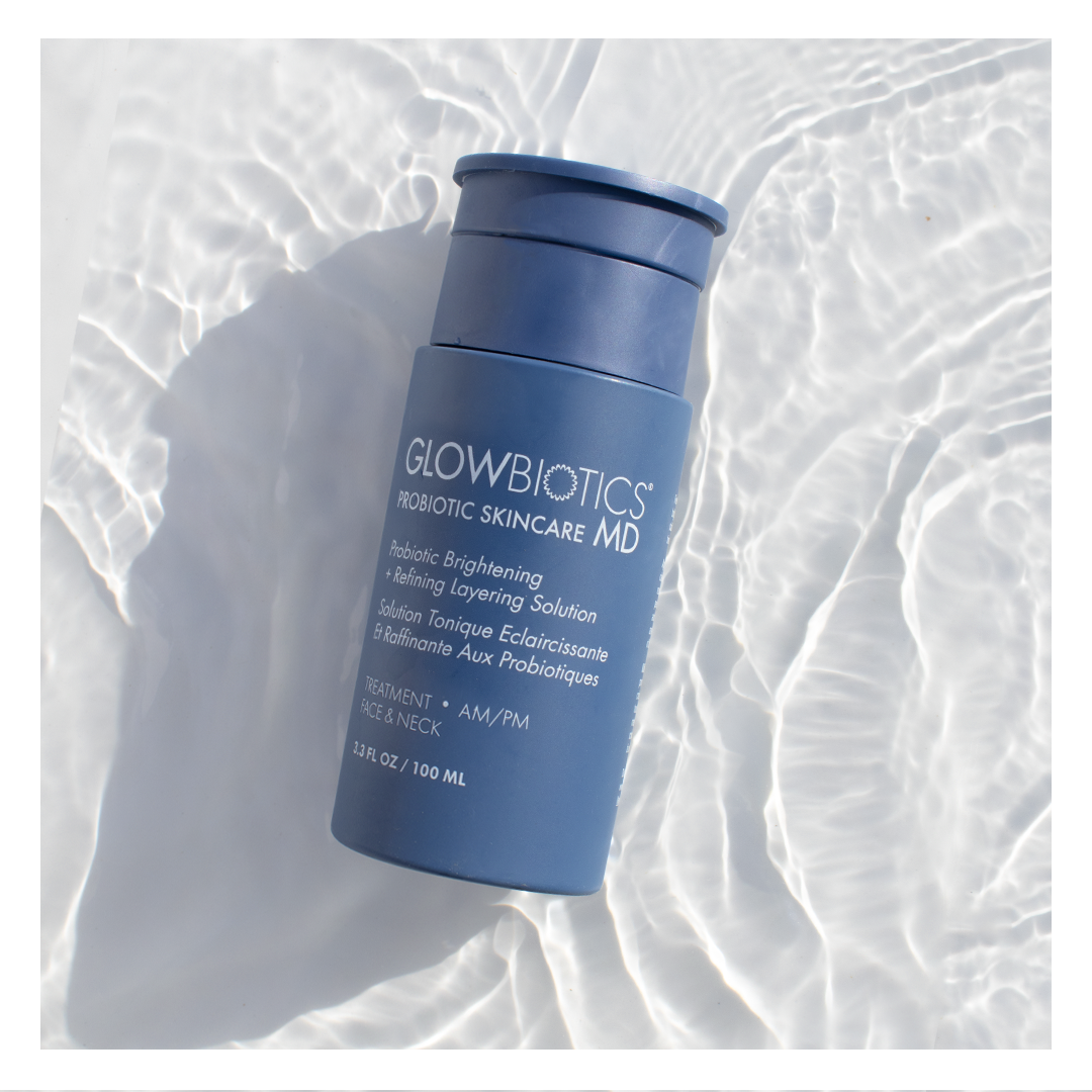 Glowbiotics Probiotic Brightening + Refining Layering Solution bottle lying at an angle on rippled water surface