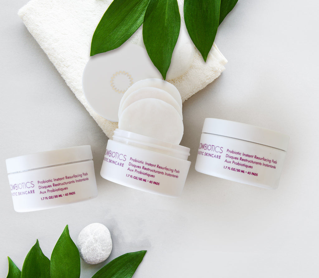 Glowbiotics Probiotic Instant Resurfacing Pads jar styled with skincare accessories and green leaves