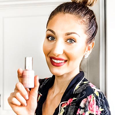 Woman showing Glowbiotics serum bottle in brightly lit room