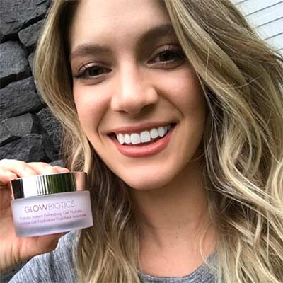 Close-up of smiling woman holding Glowbiotics probiotic clarifying pads jar.