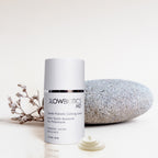 Glowbiotics Gentle Probiotic Calming Lotion bottle beside smooth stone and small dried plant on neutral background
