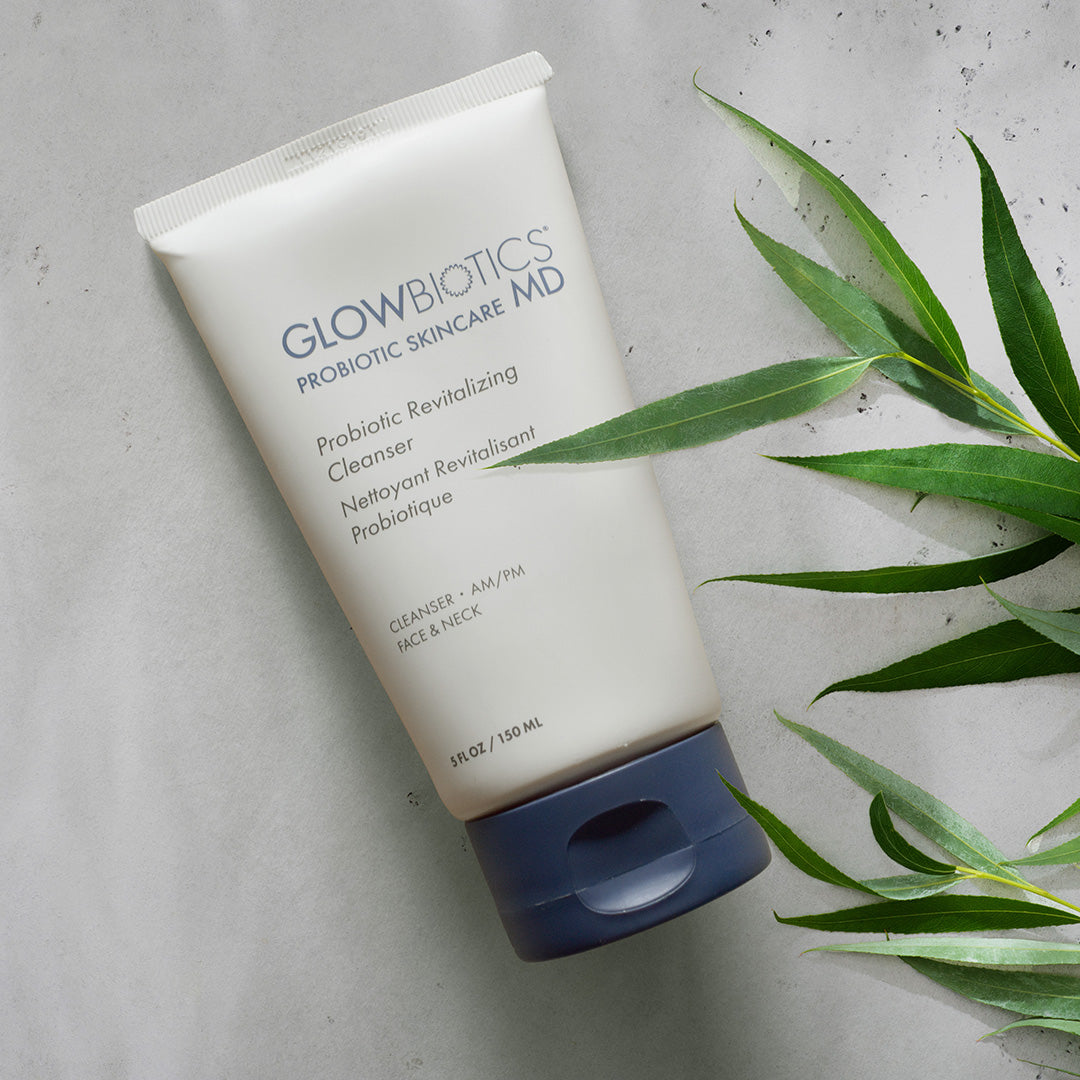 Glowbiotics Probiotic Revitalizing Cleanser tube on beige surface with green plant