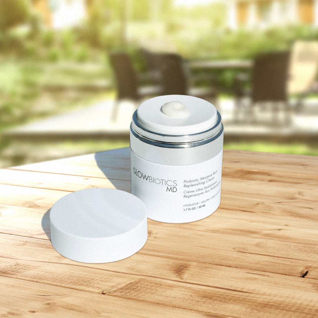 Probiotic Multi-Brightening Anti-Aging Cream jar with lid open on outdoor wood table