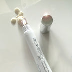 Glowbiotics Soothing + Revitalizing Eye Cream with cooling applicator tip, cap off, and cream swatches on white background