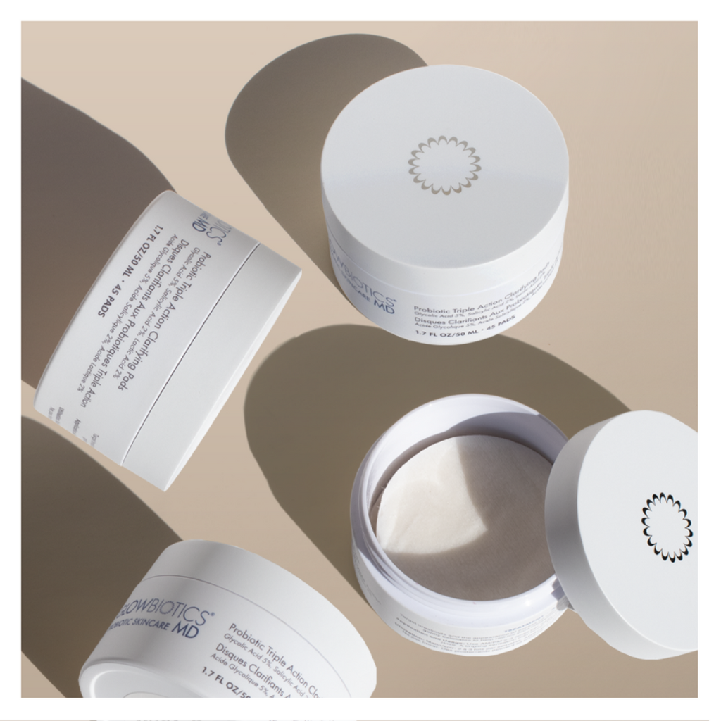 Open jar of Glowbiotics Probiotic Triple Action Clarifying Pads with lid and packaging displayed on a neutral background